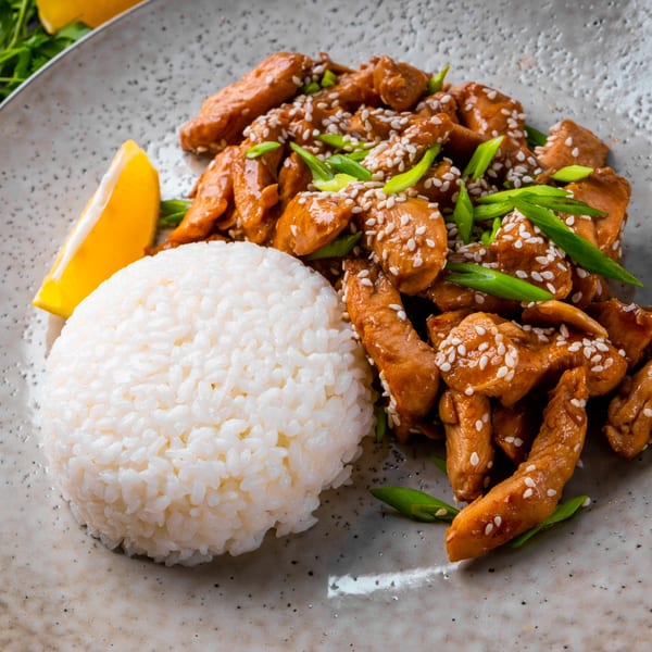 Yin Yang Express's Chinese chicken with sesame seeds, green onions, and white rice with a lemon wedge.