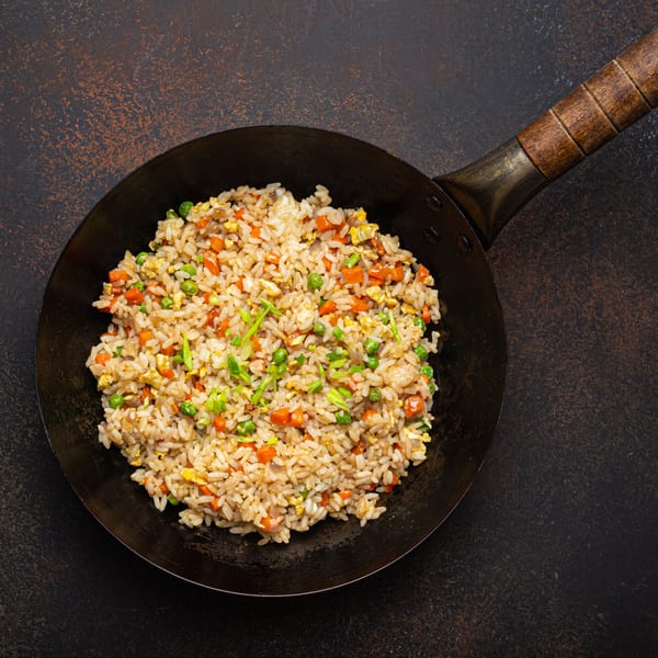 Yin Yang Express fried rice with carrots, peas, and egg in a black wok.
