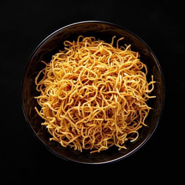 A black bowl filled with crispy golden-brown chow mein noodles, viewed from directly above.
